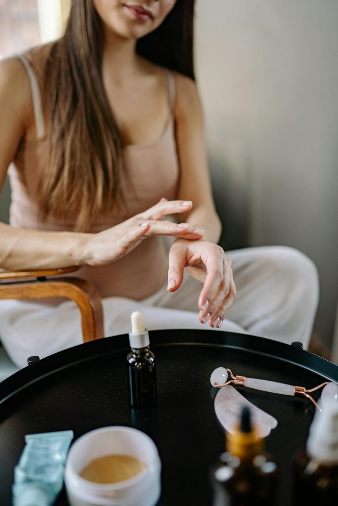 A woman applying moisturizer to her hand, representing skincare and health.